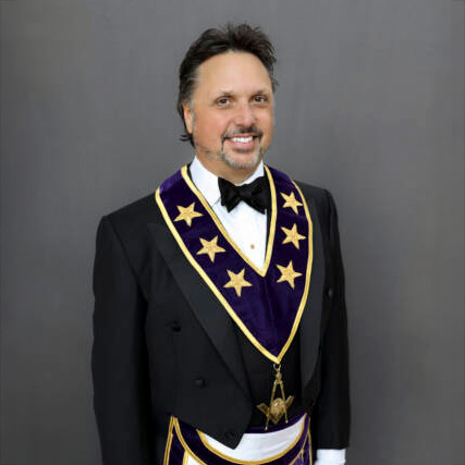 Smiling man with short dark hair in Grand Lodge Officer attire.
